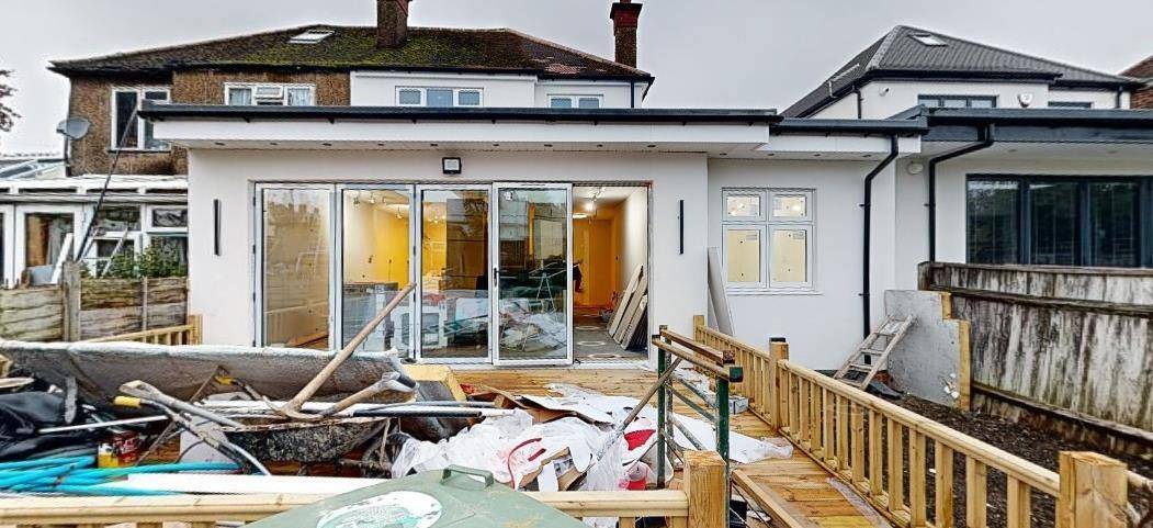 The completed wrap-around extension and rear decking during finishing works (Design and Access Statement, retrospective application)